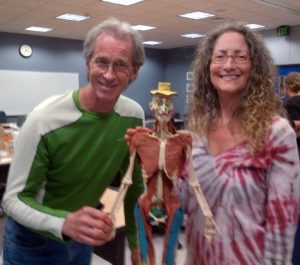 Chris Adams & Sheryl Rapée-Adams with a plastic skeleton onto which they have shaped and applied muscles of colored Plasticine